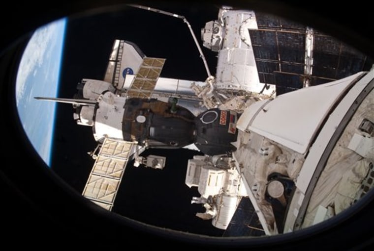 NASA astronaut Rick Mastracchio (bottom center), is seen working near the Quest airlock during the mission's third and final session of extravehicular activity. 